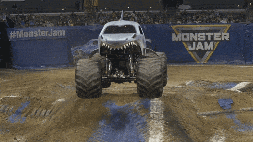 a monster jam sign is behind a monster truck in the dirt