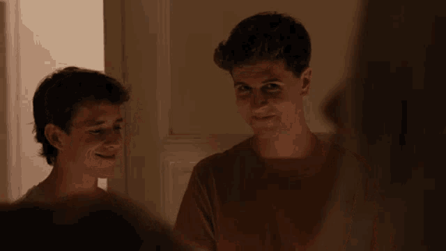 two young men are standing next to each other and smiling at each other