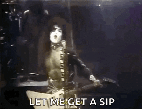 a man is singing into a microphone while playing a guitar and says let me get a sip