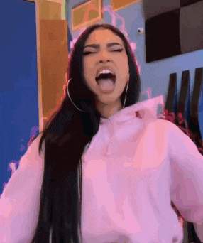 a woman wearing a pink hoodie is making a funny face .