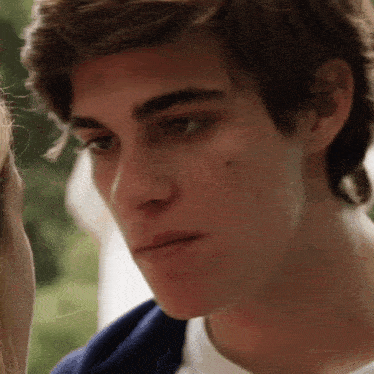 a close up of a young man 's face with a woman 's head in the background .