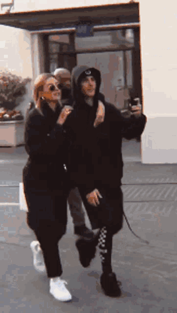 a man in a hooded jacket is walking with a woman