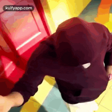 a person wearing a black hoodie is standing in front of a red door .