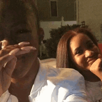 a man and a woman are sitting next to each other and the woman has long nails