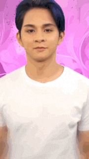 a young man in a white shirt is standing in front of a pink background .