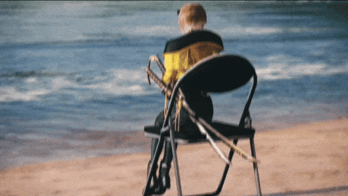 a person sits on a chair on the beach with a trombone in their lap