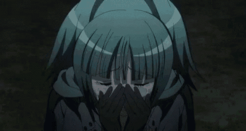 a close up of a person covering their face with their hands in a dark room .