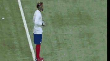 a man in a white shirt and blue shorts is jumping in the air while playing soccer .