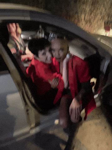 a woman in a red jacket is hugging a boy in a car