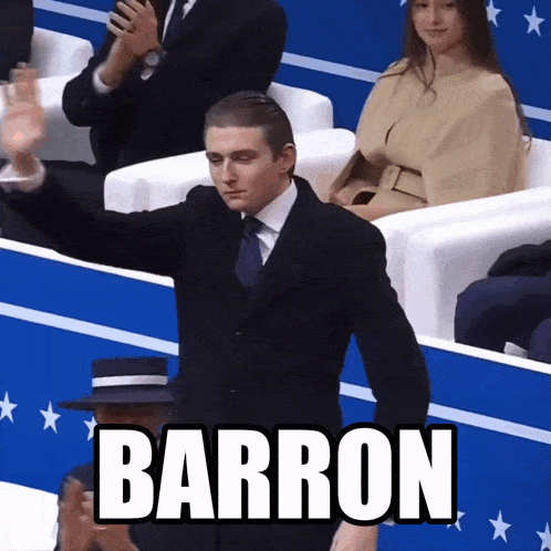 a man in a suit and tie stands in front of a crowd with the word barron written on it