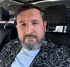 a man with a beard is sitting in a car