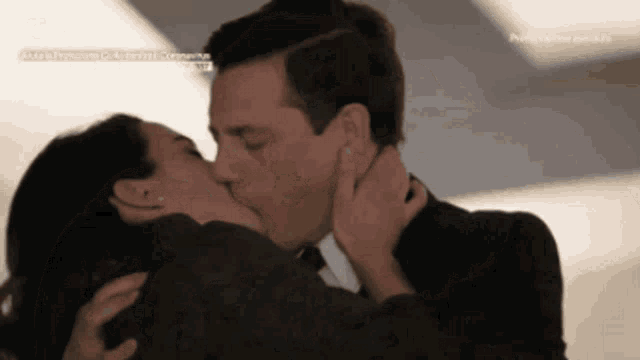 a man and a woman are kissing in front of a sign that says ' aida a primavera ' on it