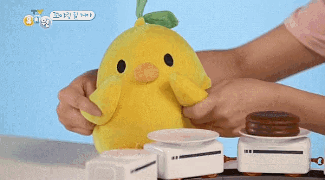 a person is holding a stuffed yellow chicken with a green head