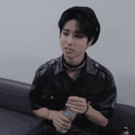 a young man is sitting on a couch and holding a bottle of water .