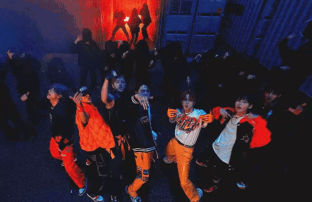 a group of young men are standing next to each other and dancing in a dark room .
