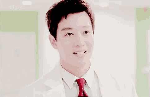 a close up of a man wearing a white coat and tie smiling .