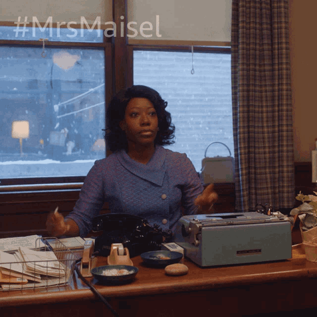 a woman sitting at a desk with the hashtag #mrsmaisel on the bottom