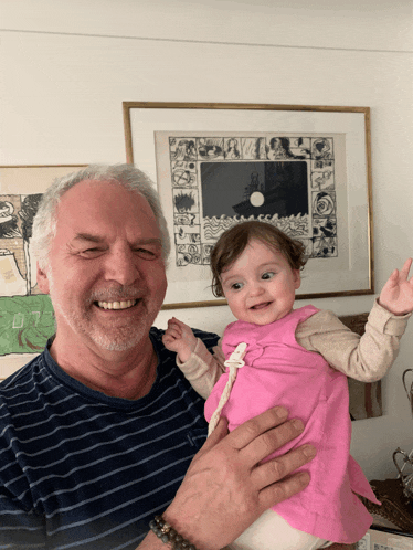 a man is holding a baby in front of a framed picture of a man