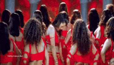 a woman in a red dress is surrounded by other women in red dresses .