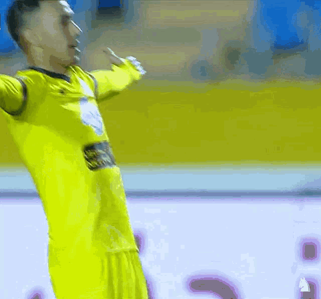 a soccer player wearing a yellow jersey with a white logo on the chest