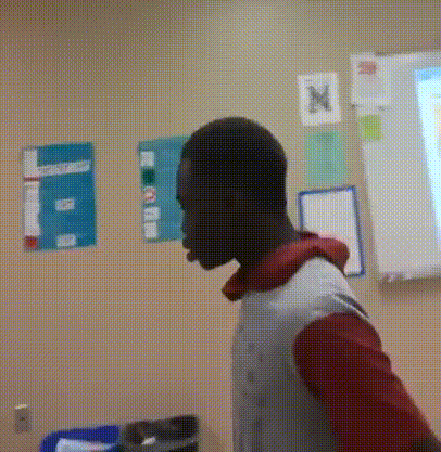 a man is standing in front of a classroom with posters on the wall including one that says ' a ' on it