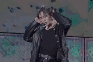 a man is standing on a stage wearing a black leather jacket and pants .