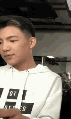 a young man wearing a white hoodie is looking at something .