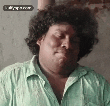a man with curly hair is making a funny face with his mouth open .