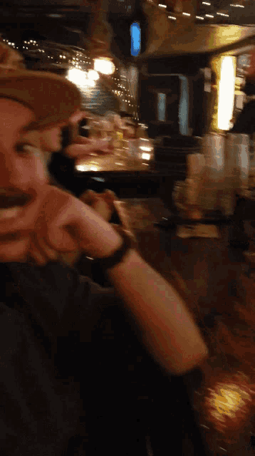 a man in a cowboy hat sits at a bar drinking a beer