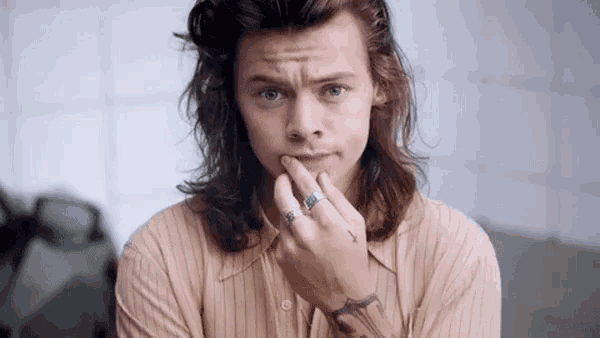 a young man with long hair is wearing a ring on his finger