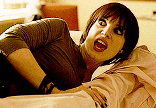 a woman with short hair is laying on a bed with her mouth open