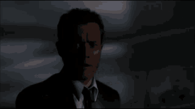 a person 's hand is pointing at a glowing object in a dark room with a newspaper on a table in the background