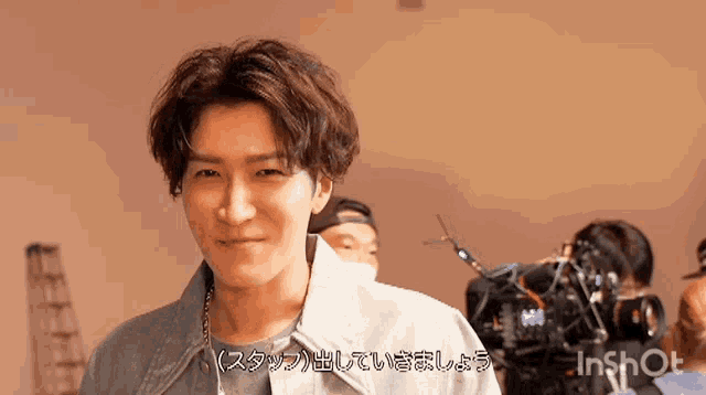 a man in a denim jacket is smiling in front of a camera that says inshot on the bottom