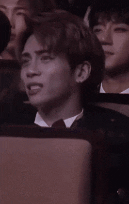 a man in a suit and tie is sitting in a row of people .