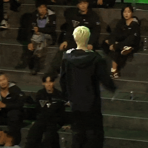 a man in a black jacket stands in front of a green light