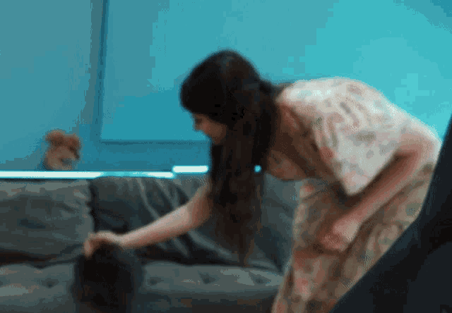 a woman in a floral dress is cleaning a couch in a living room