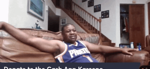 a man in a purple phoenix jersey sits on a couch with his arms outstretched