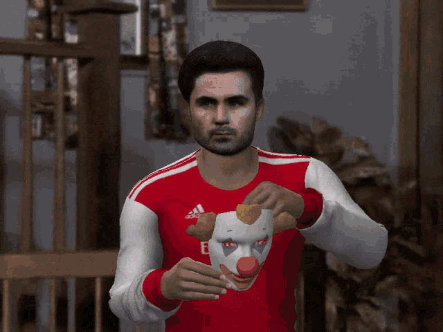a man wearing a red and white adidas shirt holds a clown mask