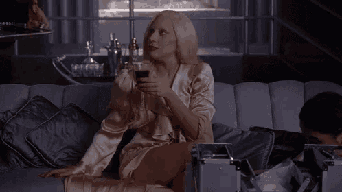 a woman is sitting on a couch with a glass of wine .