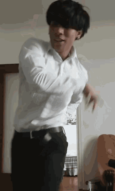 a man in a white shirt is dancing in a living room