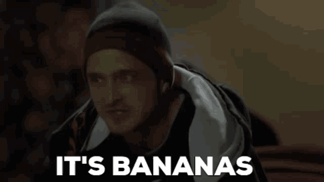 a man wearing a beanie is saying it 's bananas in a dark room .