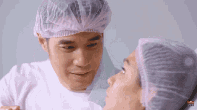 a man wearing a surgical cap looks at a woman