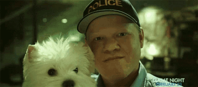 a man wearing a police hat holds a white dog