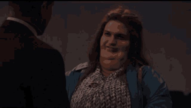 a woman is making a funny face while talking to a man in a suit