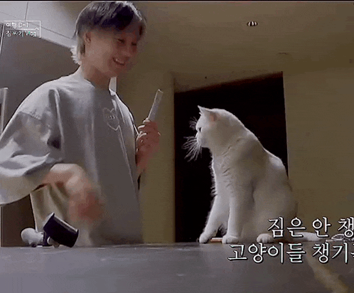 a man is playing with a white cat in a kitchen