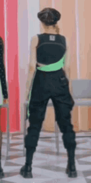 a woman in a black top and black pants is standing in a room .