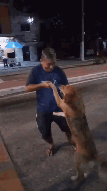 a man in a blue shirt is standing next to a dog