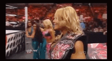 a woman is standing in front of a crowd in a wrestling ring on a television screen .