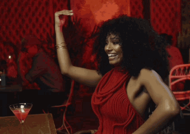 a woman in a red dress is dancing in a bar