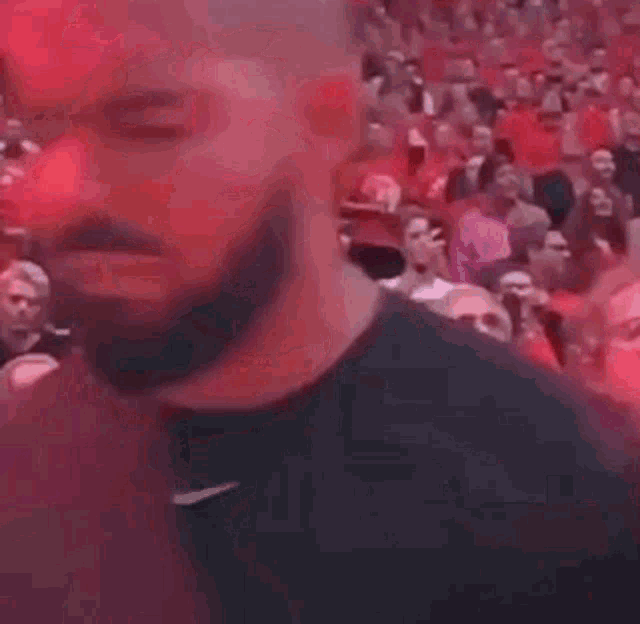 a man with a beard is standing in front of a crowd in a stadium .